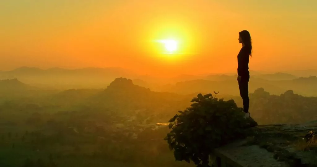 Girl on cliff with sunset behind her