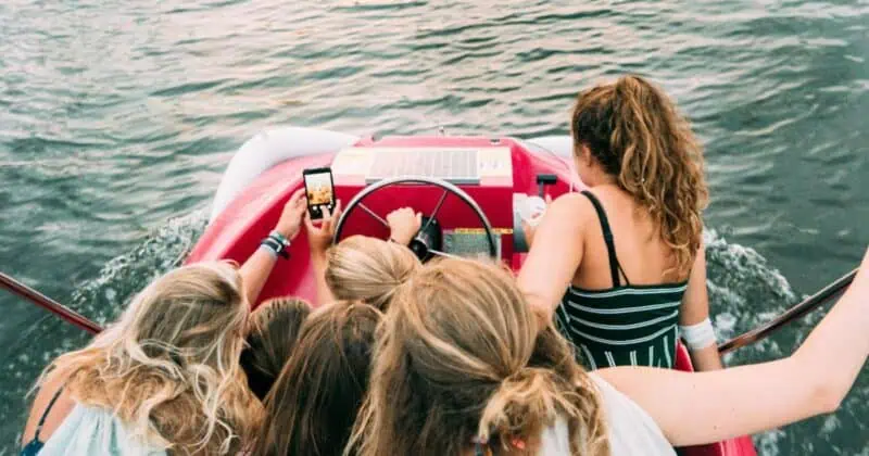 Group of young women on a boat looking at a smartphone together