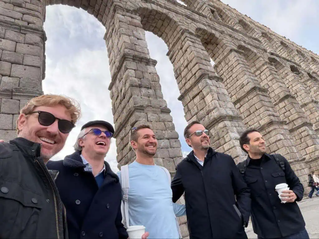 Group of men posing for a photo in front of ancient stone ruins.