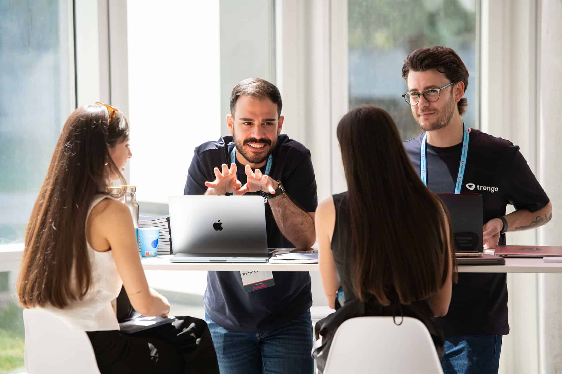 Professionals talking and networking at a business event around a table with laptops